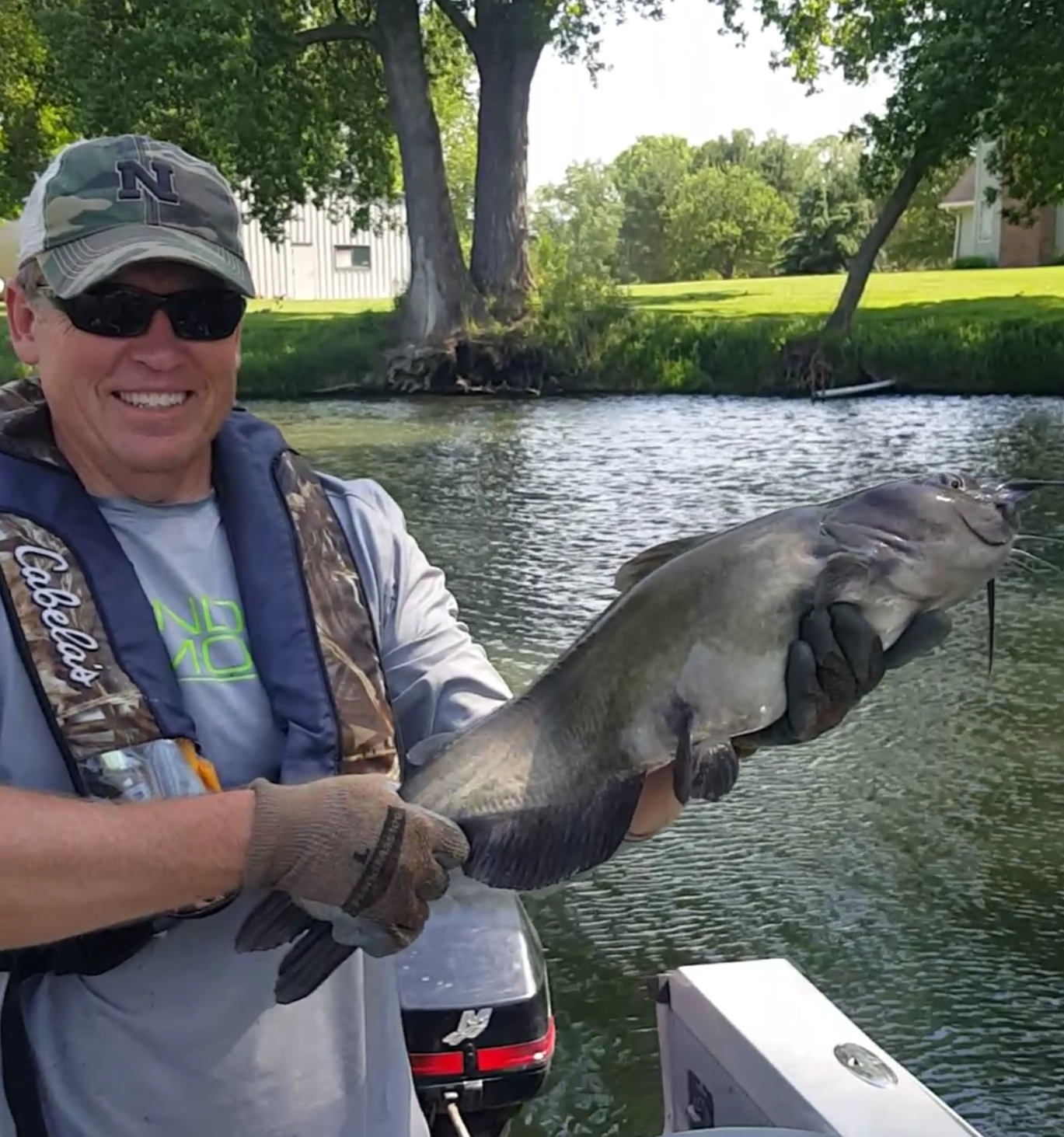 Nebraska Conservation Officer Rich Berggren of Waterloo wearing rubber fish handling gloves holding a nice-sized channel catfish he landed, then released. Photo by Greg Wagner.