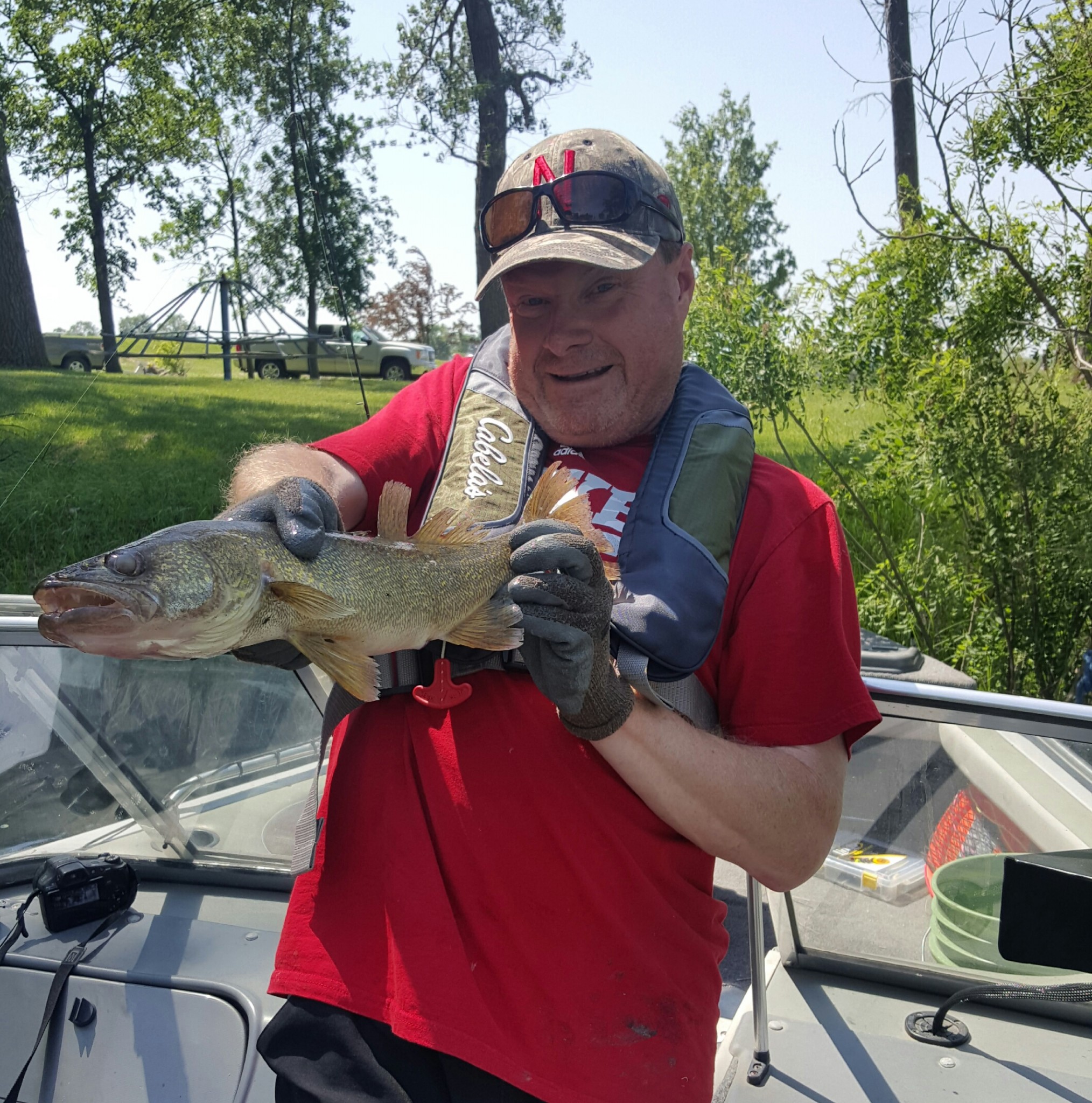 Greg Wagner, wearing rubber fish handling gloves, poses quickly with a walleye he caught before releasing it back into the water. Photo by Rich Berggren.