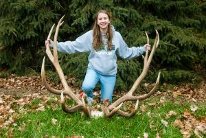 Hannah Helmer of Seward holds the antlers of a bull elk she shot in the Hat Creek Unit near Crawford on September 24, 2016. The elk scored 430 6/8 on the Boone & Crockett scale, making it the new state record for non-typical American elk and putting it 16th on Boone & Crockett's current (13th edition, Records of North American Big Game) all-time records list. Fowler, November 30, 2016. Copyright NEBRASKAland Magazine, Nebraska Game and Parks Commission.