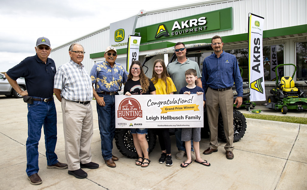 From left, Bob Allen, Nebraska Game and Parks commissioner; Jim Douglas, Game and Parks director; Rick Brandt, commissioner; Jody Hellbusch; Kaylee Hellbusch, 12; Leigh Hellbusch, winner of the Take 'em Hunting grand prize; Connor Hellbusch, 10; and Kent Kirchhoff, vice president of sales and marketing with AKRS Equipment, during a ceremony June 24, 2021, at the AKRS store in Gretna, Nebraska. | Jeff Kurrus, Nebraskaland, Nebraska Game and Parks Commission