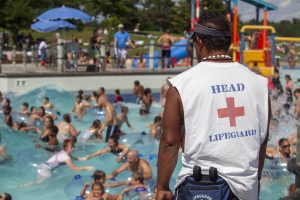 A lifeguard watches the water where dozens of people swim.