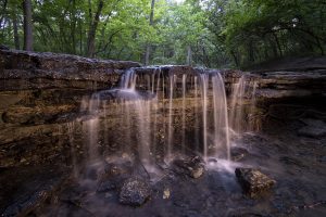 The iconic waterfall on Stone Creek, illuminated here using light painting, is easily accessible via the quarter-mile Stone Creek Falls Trail at Platte River State Park.