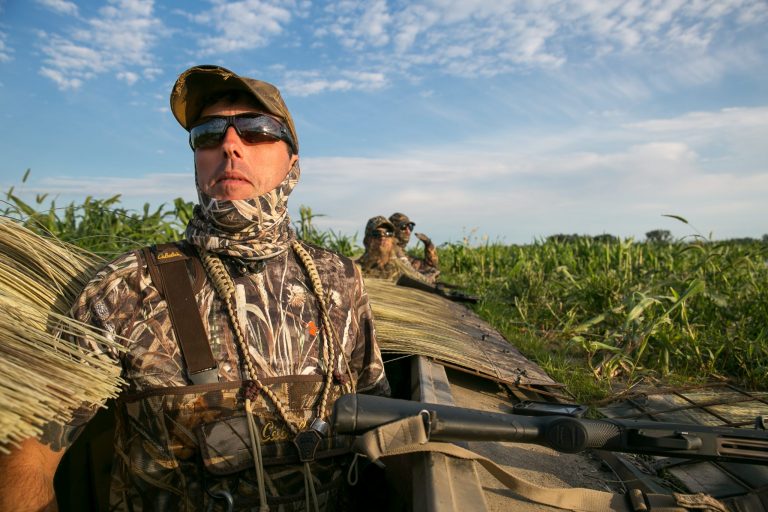 Two men looking out of a pit blind.