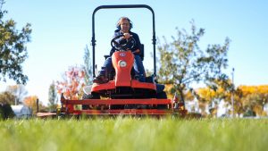 A woman mows the lawn at a state park area.
