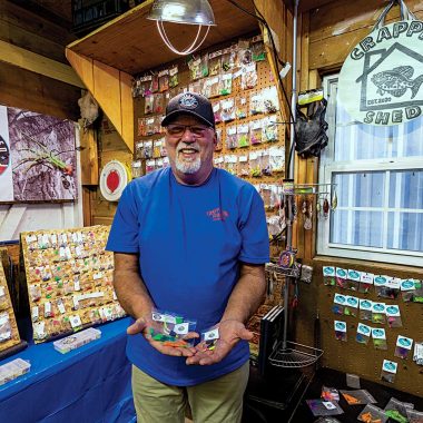 A man poses proudly in his crappie fishing shed bait shop.