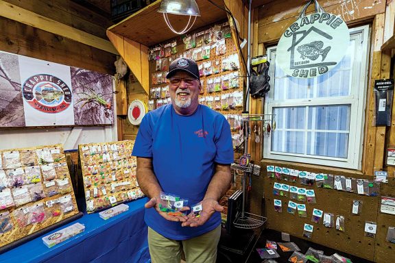 A man poses proudly in his crappie fishing shed bait shop.