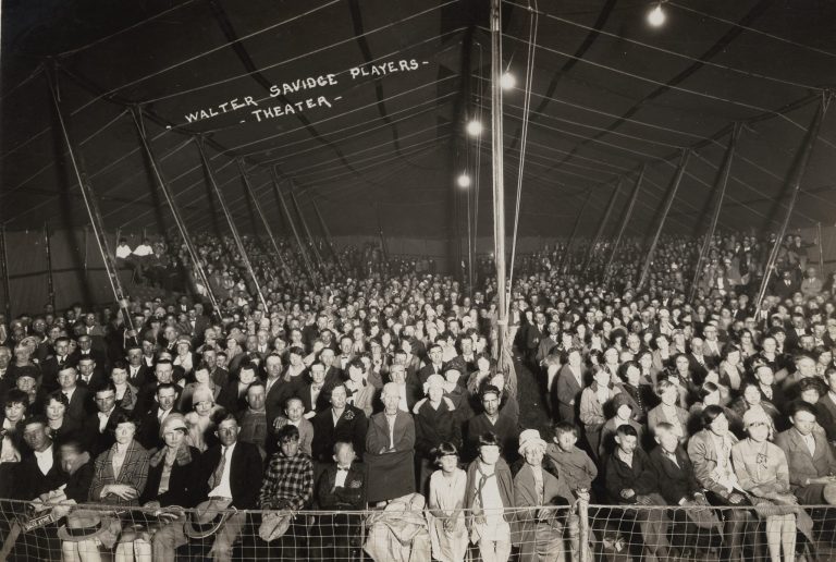 A crowd of people in a tent at a carnival in the early 1900s.