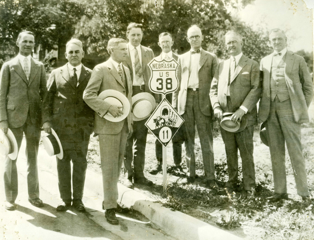 Men in suits pose next to a newly installed highway marker for U.S. Highway 38 through Nebraska