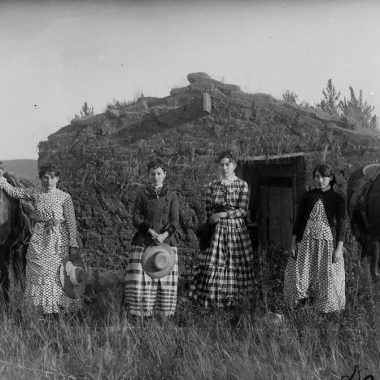 Four sisters pose in front of a sod house on the Nebraska prairie in 1886.