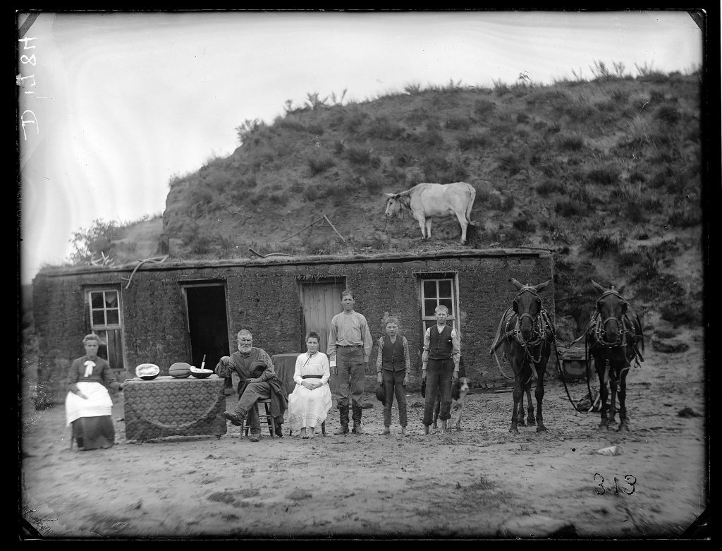 A family poses in front of their sod house in 1784 in Nebraska.