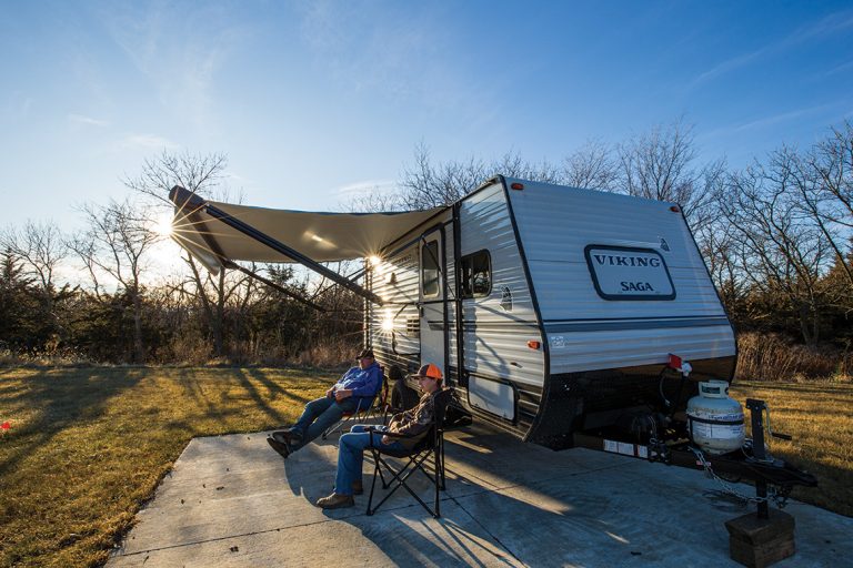 RV campers relax outside in lawn chairs at their campsite.