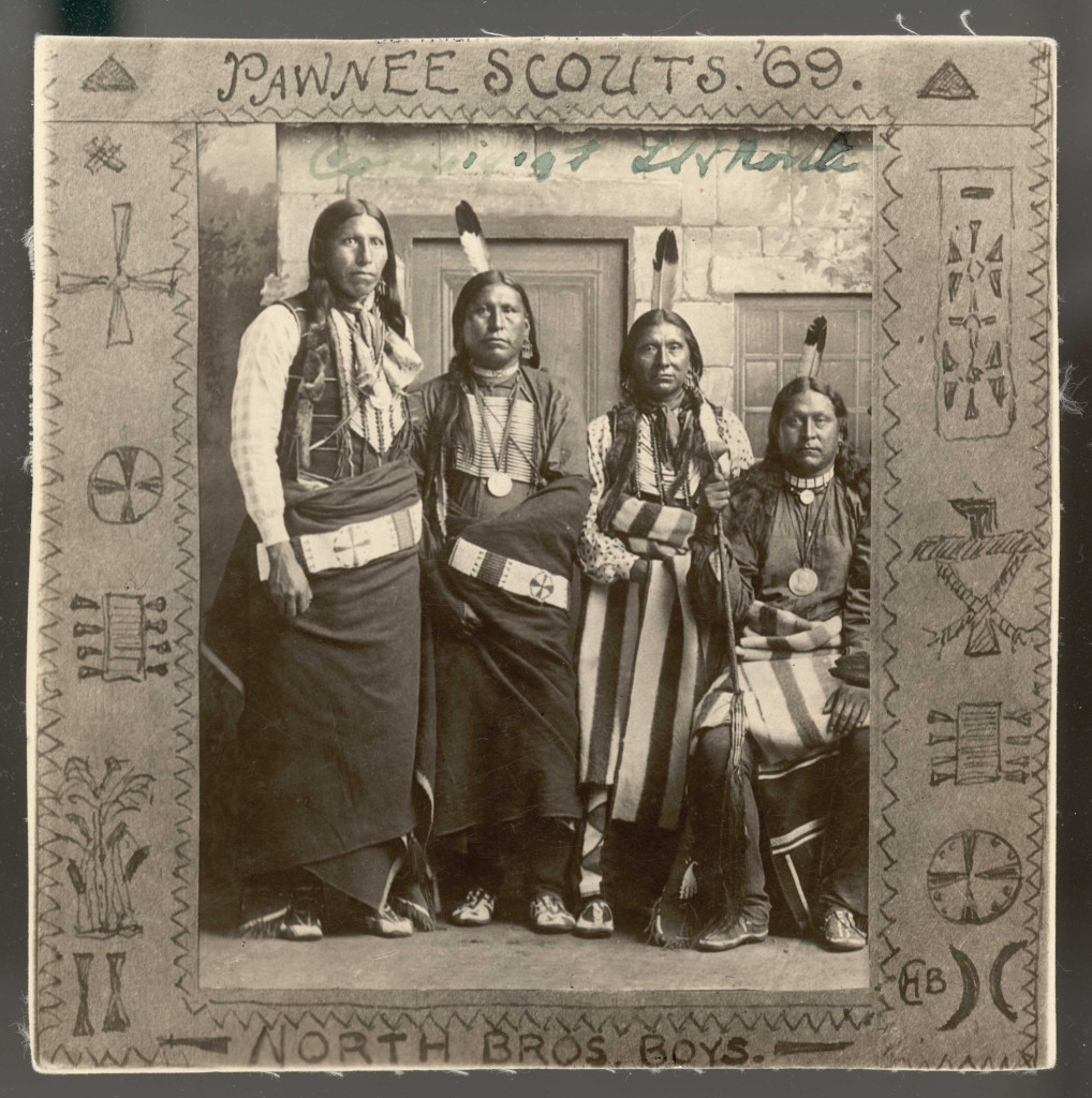 Four Native American men in traditional clothing pose for a photograph