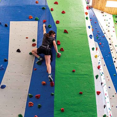 A girl climbing a rock wall.