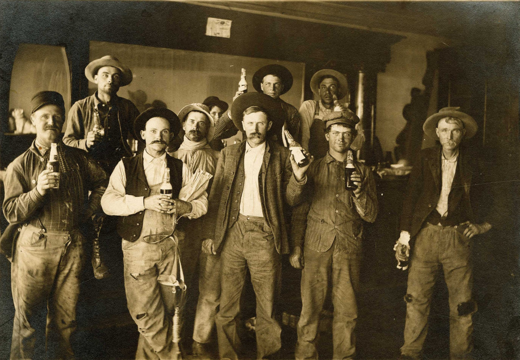 Men pose for the camera with their beer bottles during the Prohibition era in this sepia-toned photo