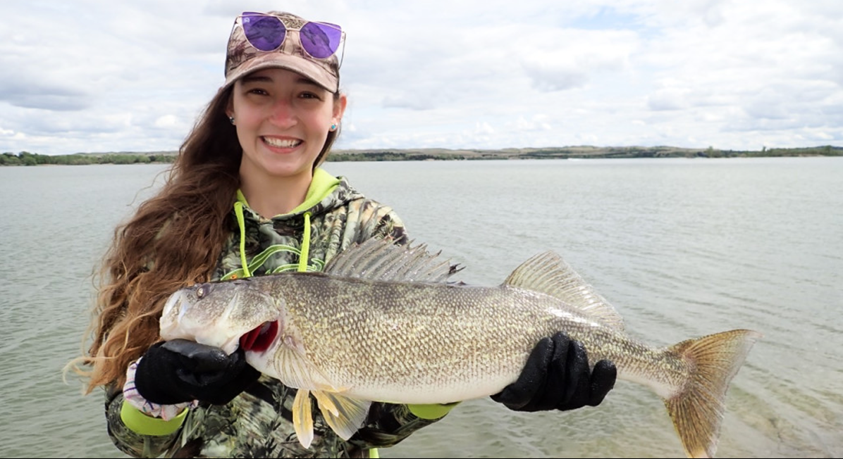 A girl smiles as she holds up a large walleye she caught while fishing in Nebraska.