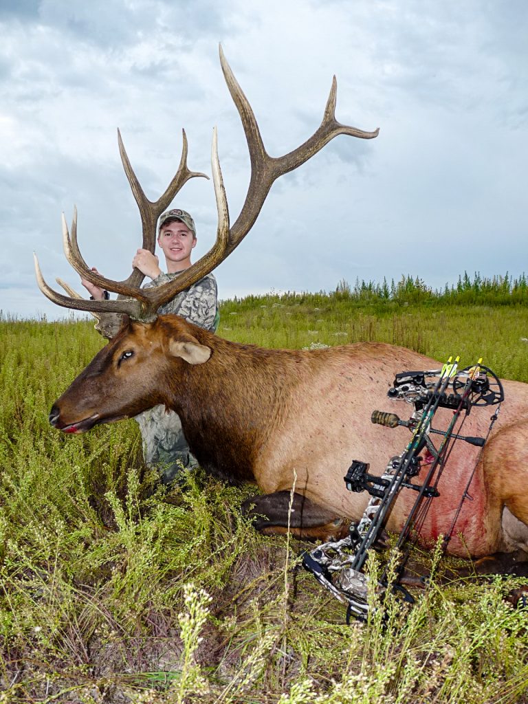 A 21-year-old male archery hunter poses with a male elk that he shot.