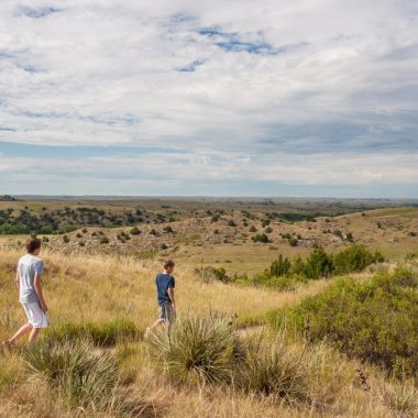 A family hikes a trail to view the Oregon Trail ruts on Windlass Hill at Ash Hollow State Historical Park.