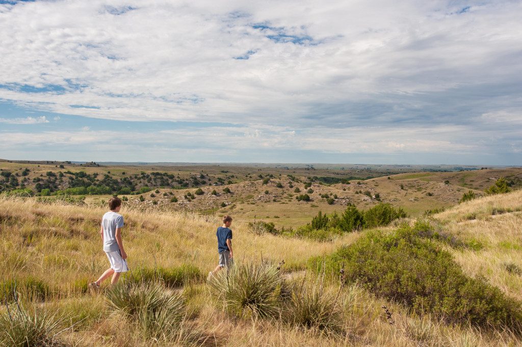 A family hikes a trail to view the Oregon Trail ruts on Windlass Hill at Ash Hollow State Historical Park.