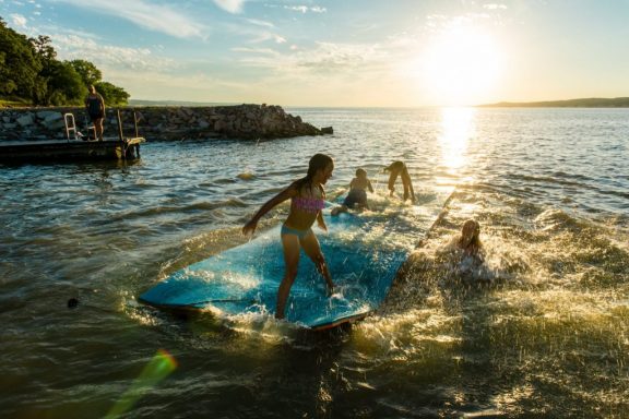 Kids play on a floating mat in a lake.