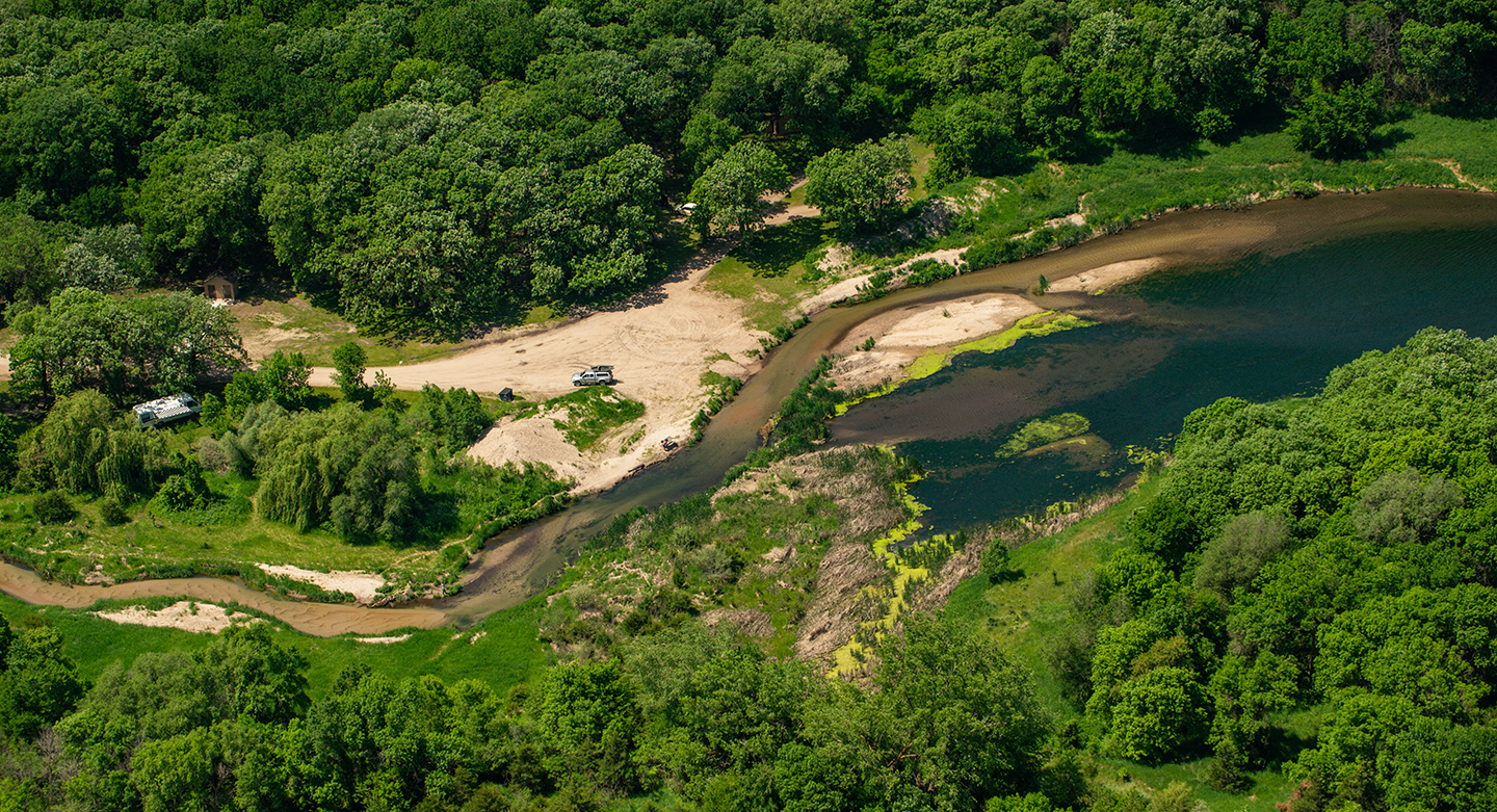 Aerial photo of a tree-lined creek during summer on a wildlife management area in Nebraska.