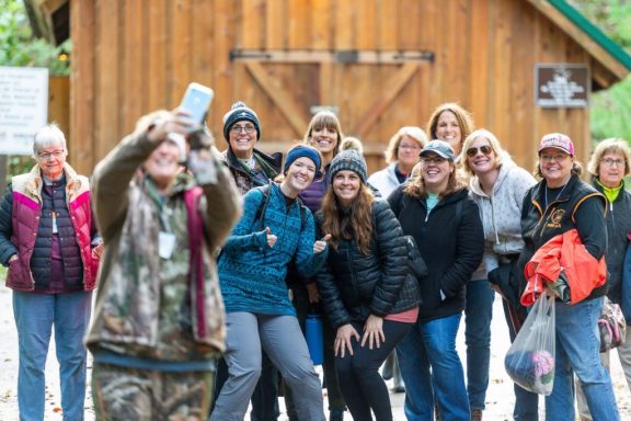 A group of women pose for a photo at an outdoor workshop.