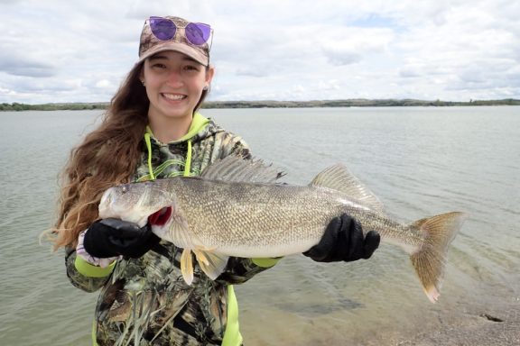 A girl smiles as she holds up a large walleye she caught while fishing in Nebraska.