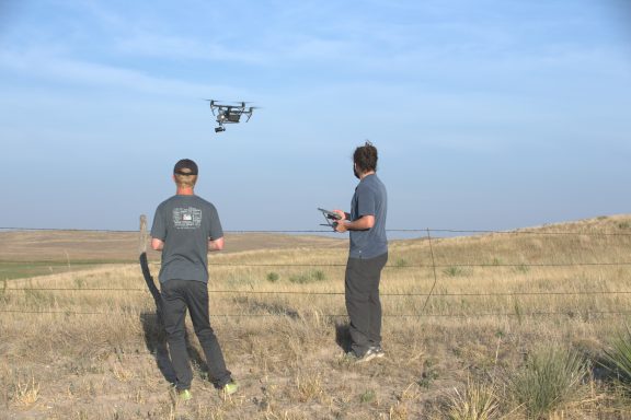 Two men fly a drone.