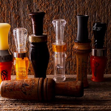 Display of duck calls on a wooden shelf.