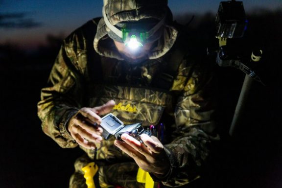 A hunter inspects his GoPro camera with a head lamp in the early morning.