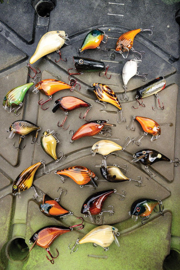 About two dozen glossy, wooden, homemade lures are displayed on top of a kayak