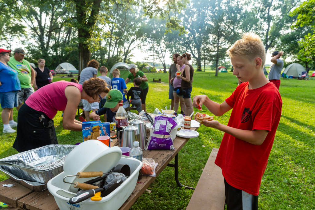 Campers preparing lunch at a picnic table.