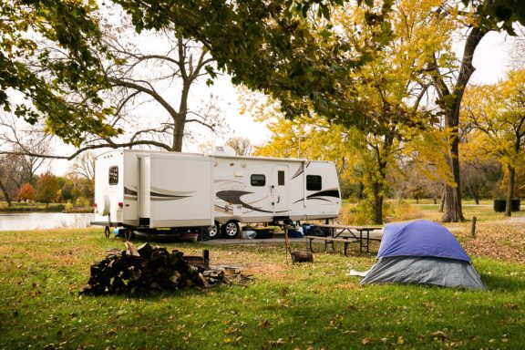 An RV and tent at a campsite in the fall.