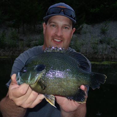 A man catches a green sunfish x bluegill hybrid.