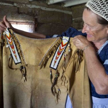 A woman holds up a Native American leather top.