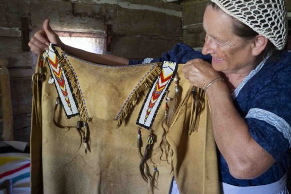 A woman holds up a Native American leather top.