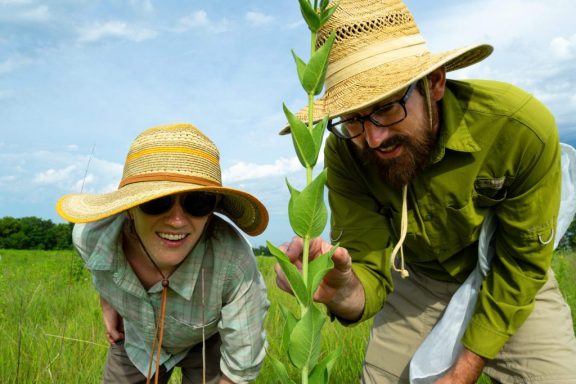 a man and woman inspect a large green leafy plant