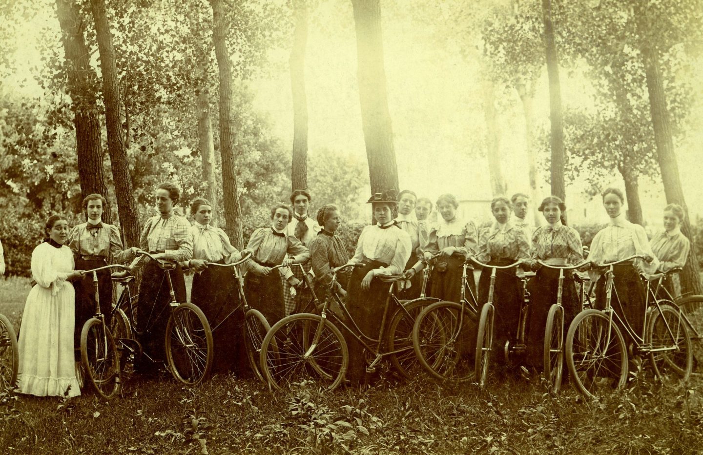 A group of women pose with their bicycles in a forested Nebraska area in 1895.