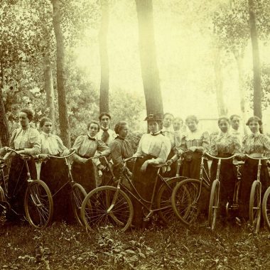 A group of women pose with their bicycles in a forested Nebraska area in 1895.