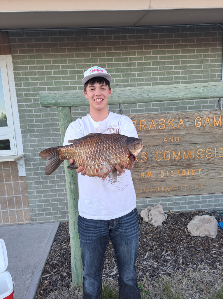 A young man holding a state record goldfish.