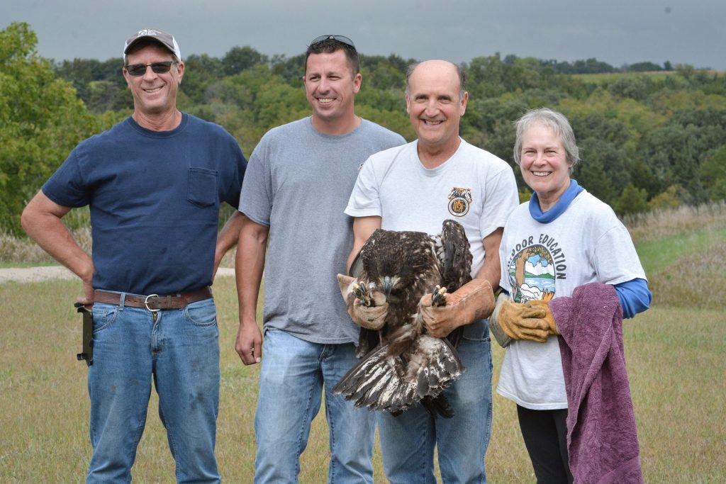 A group of people pose with an bald eagle that they are about to release back into the wild.