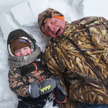 A man and small boy playing in the snow during winter