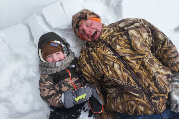 A man and small boy playing in the snow during winter