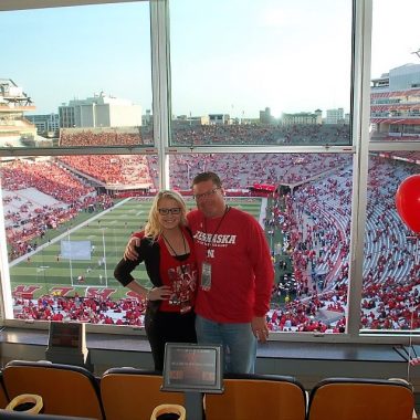 A dad and college-aged daughter pose at a Nebraska Cornhusker Football Game.