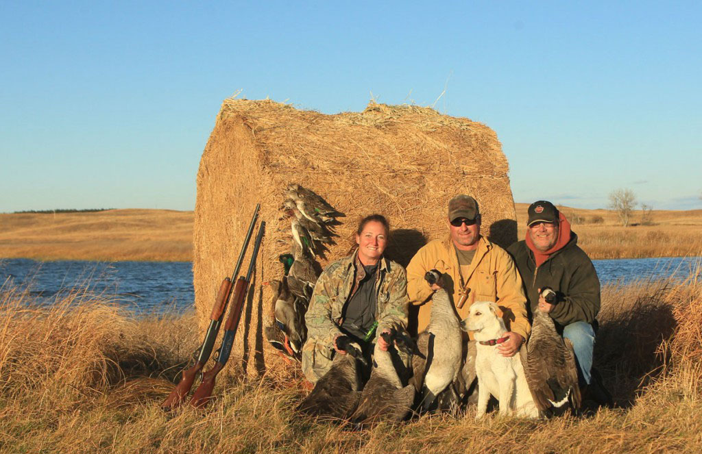 Two men and a woman waterfowl hunting.