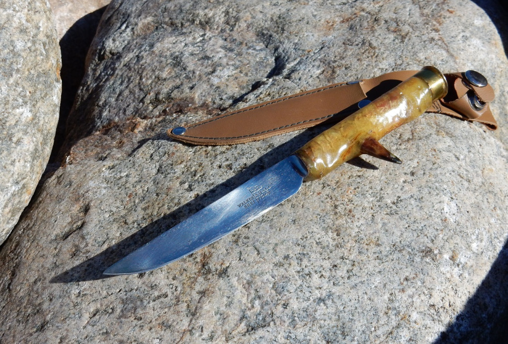 A hand-made turkey hunting knife on a rock.