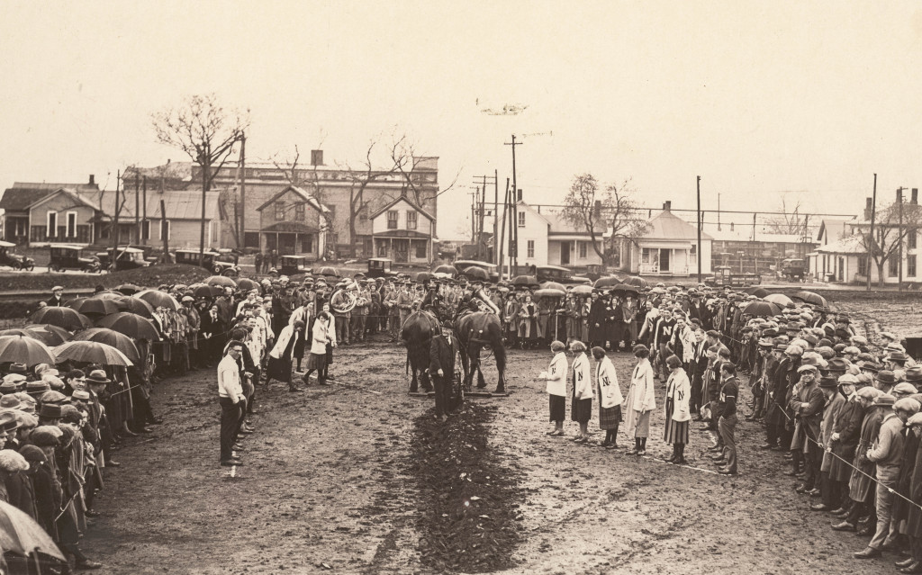 a ditch in the dirt is dug by people wearing vintage Nebraska university clothing