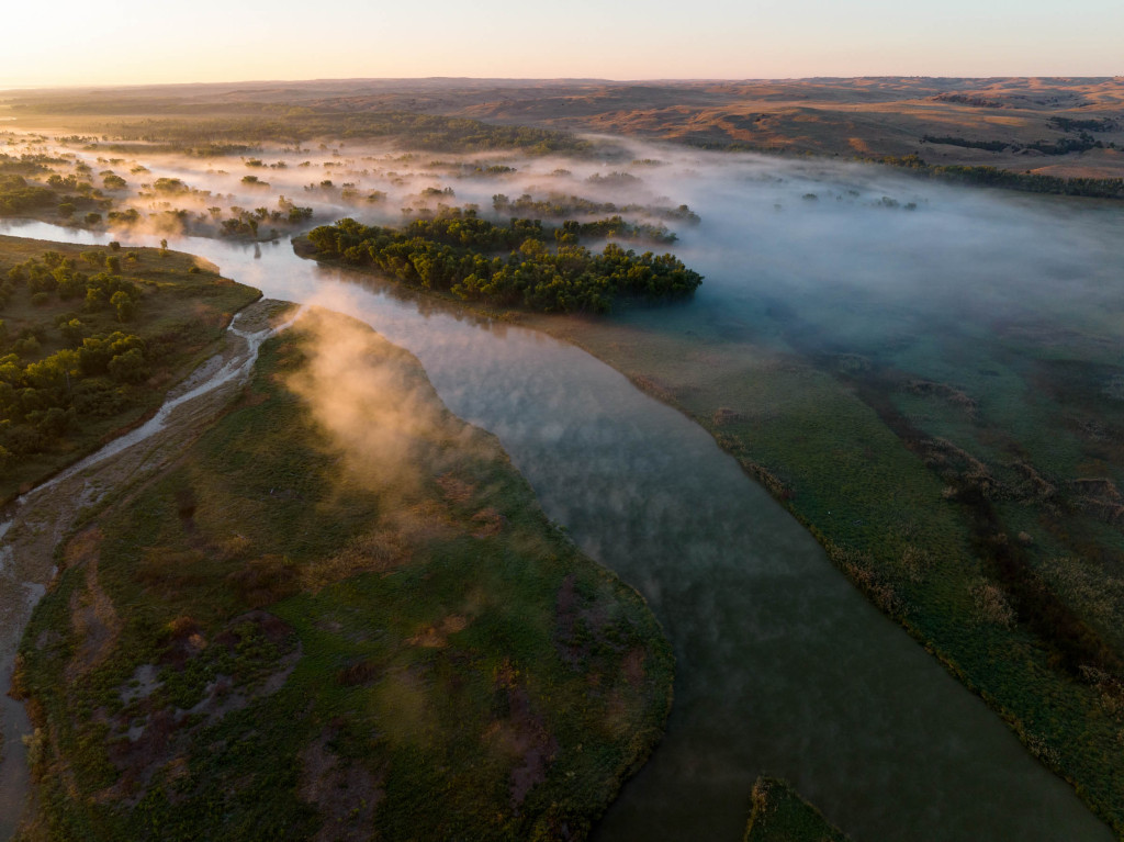 fog rises from a branched river