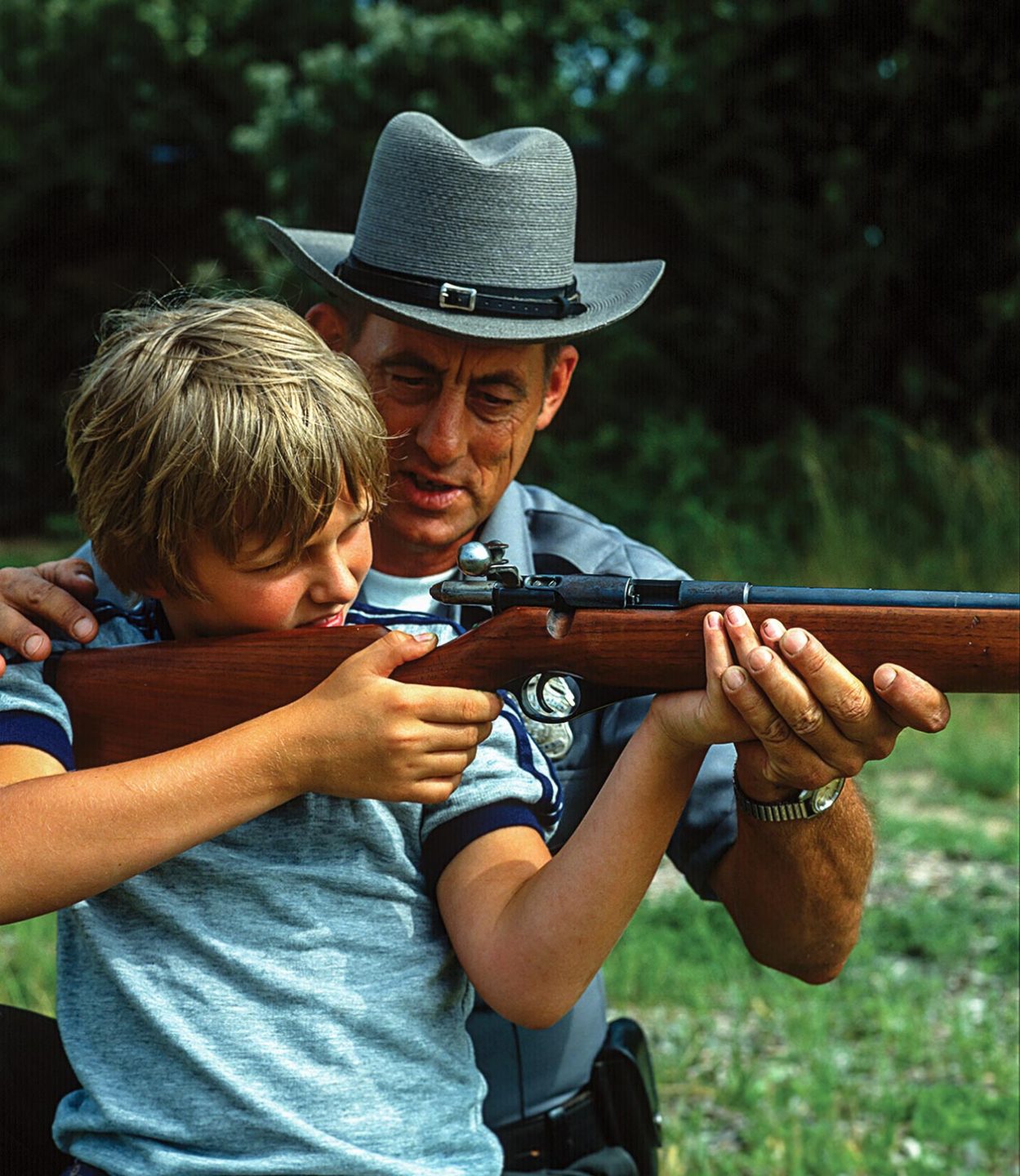 A conservation officer teaching a boy to shoot.