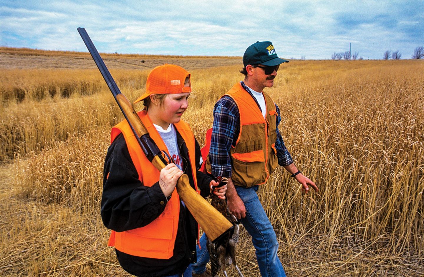 A male hunter education mentor teaching a girl how to upland hunt.