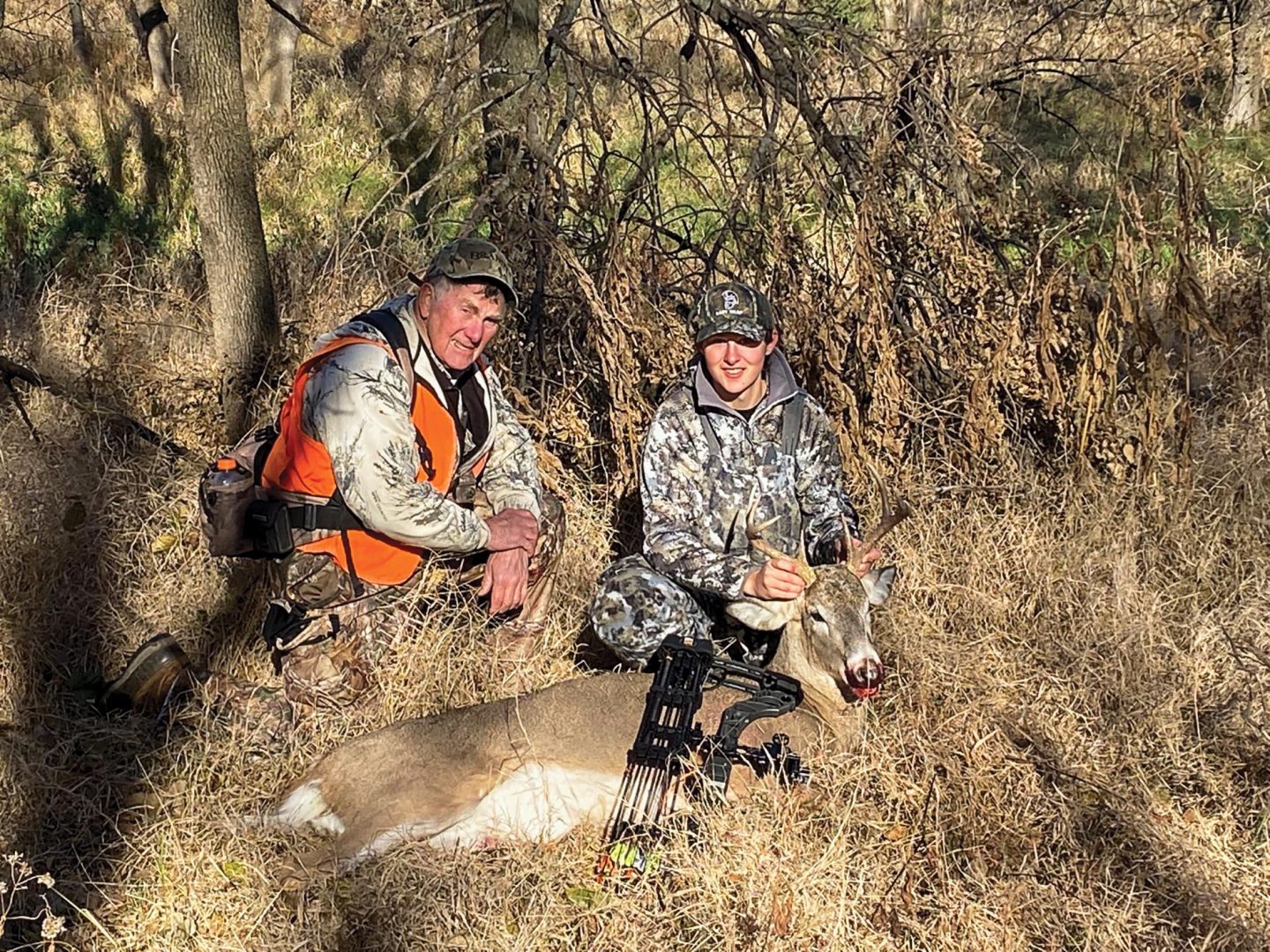 An older man mentoring a young woman deer hunting.